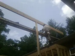 Carpenter setting a ridge beam over a new addition frame — Ice Dam Removal by Roofing Brothers in Lilly