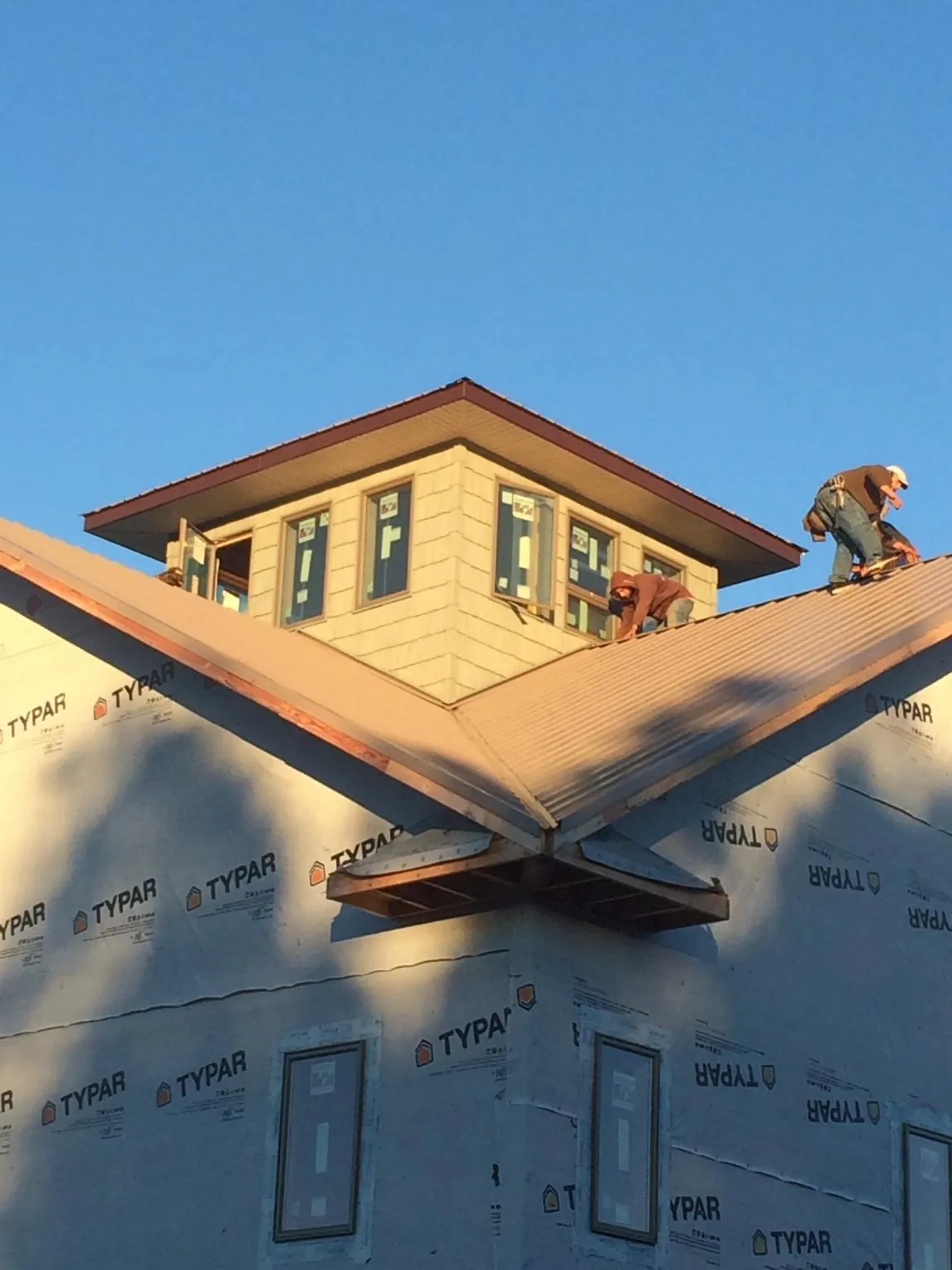 Roofers working around a rooftop cupola on a new metal roof at sunset — Roof Waterproofing in Lilly by Roofing Brothers